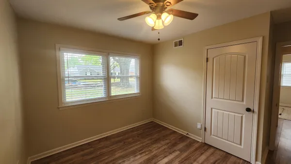 a view of an empty room with window and chandelier fan