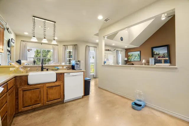 a kitchen with kitchen island granite countertop a sink and white cabinets with chairs