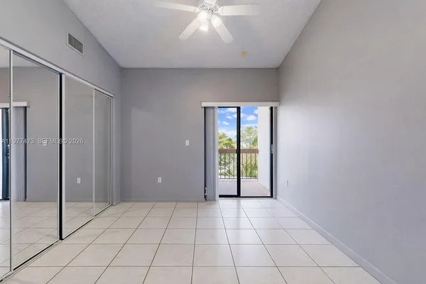 a view of an empty room with window and chandelier fan