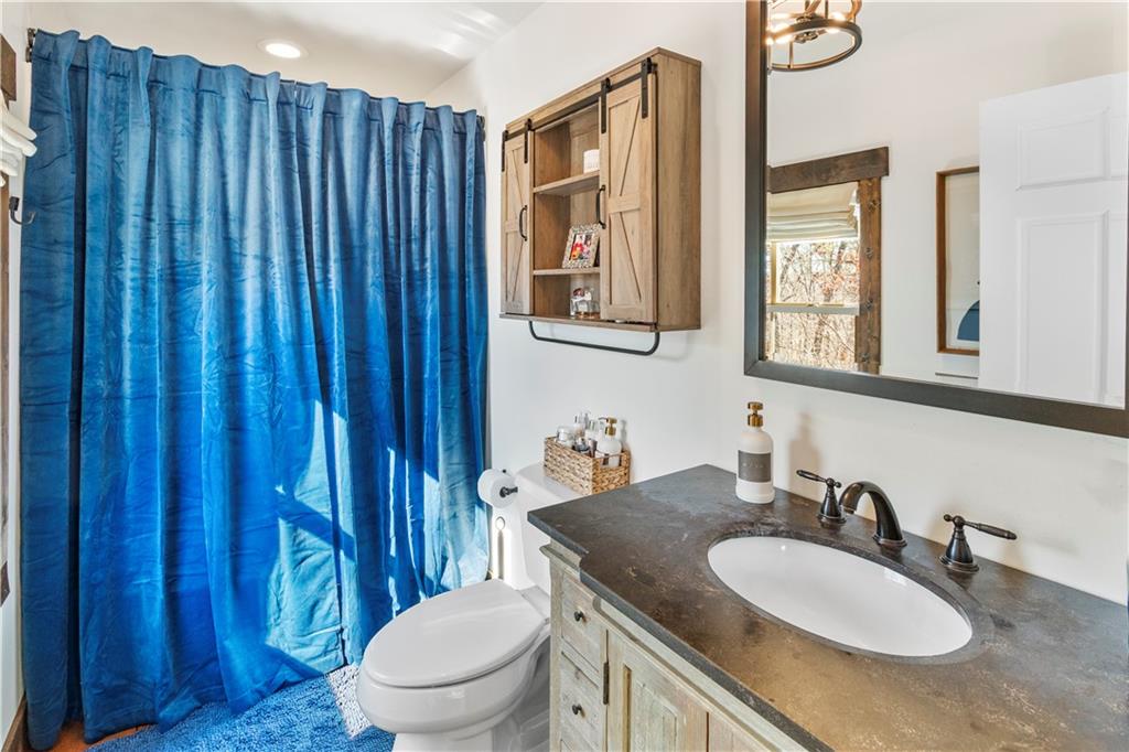 308 Hugh Stowers Road Dawsonville, GA 30534 - Photo 37 of 81 a bathroom with a granite countertop toilet a sink and a mirror