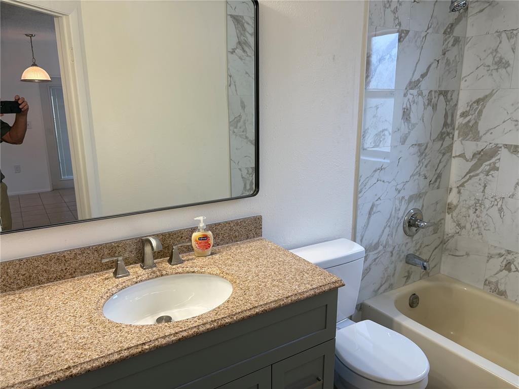 10305 Bannister Street Spring Hill, FL 34608 - Photo 23 of 24 a bathroom with a granite countertop sink toilet and bathtub