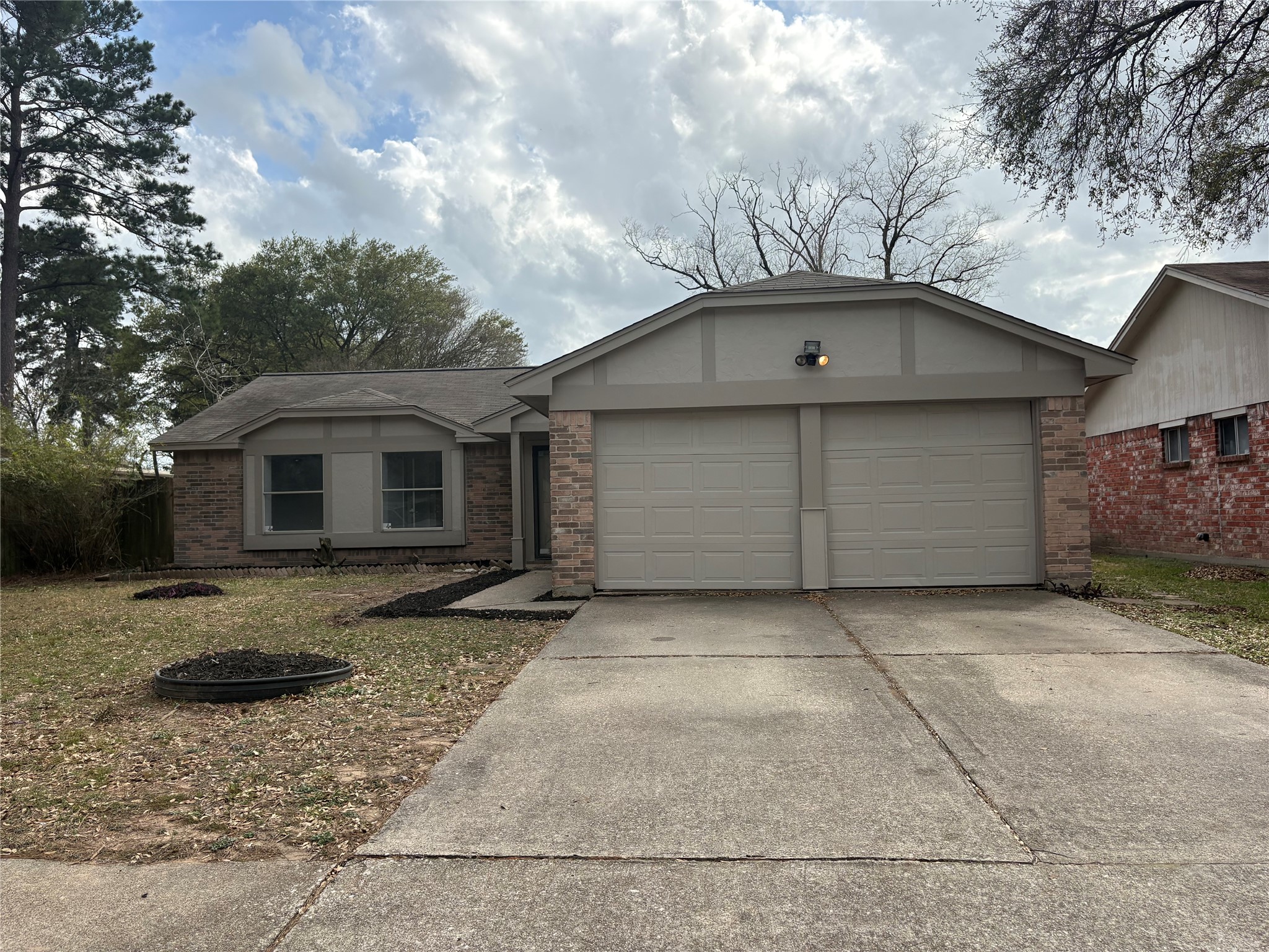 Single story home with concrete driveway, brick siding, and a garage