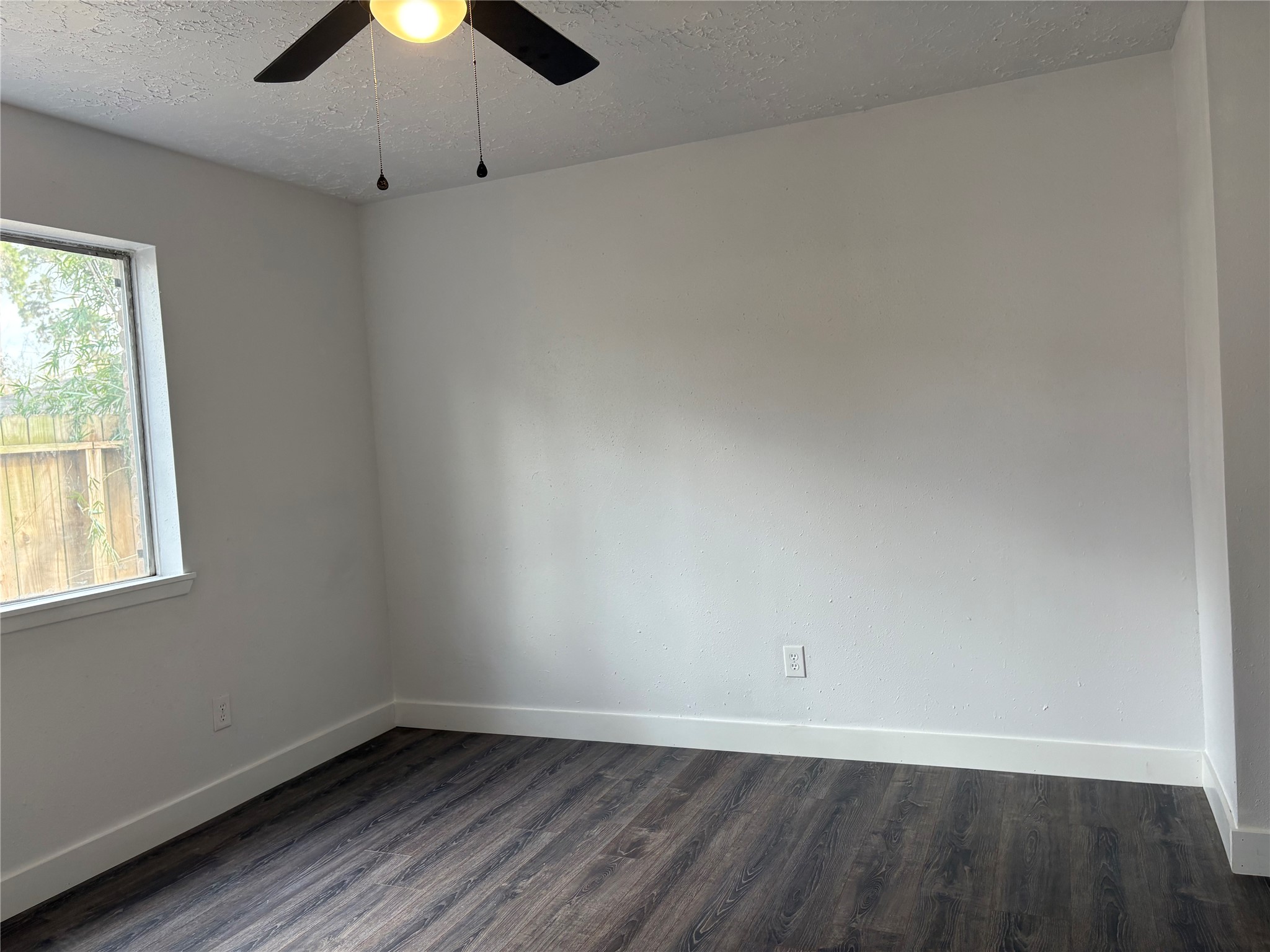 4631 Enchanted Rock Lane Spring, TX 77388 - Photo 6 of 10 Unfurnished room with dark wood-style flooring, ceiling fan, and a textured ceiling
