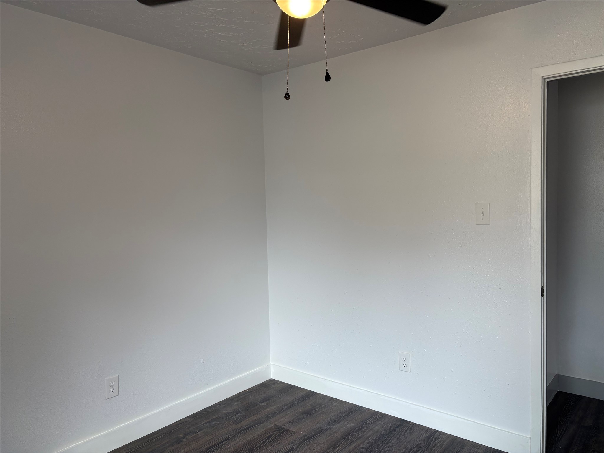 4631 Enchanted Rock Lane Spring, TX 77388 - Photo 7 of 10 Empty room featuring dark wood finished floors, a ceiling fan, and a textured ceiling