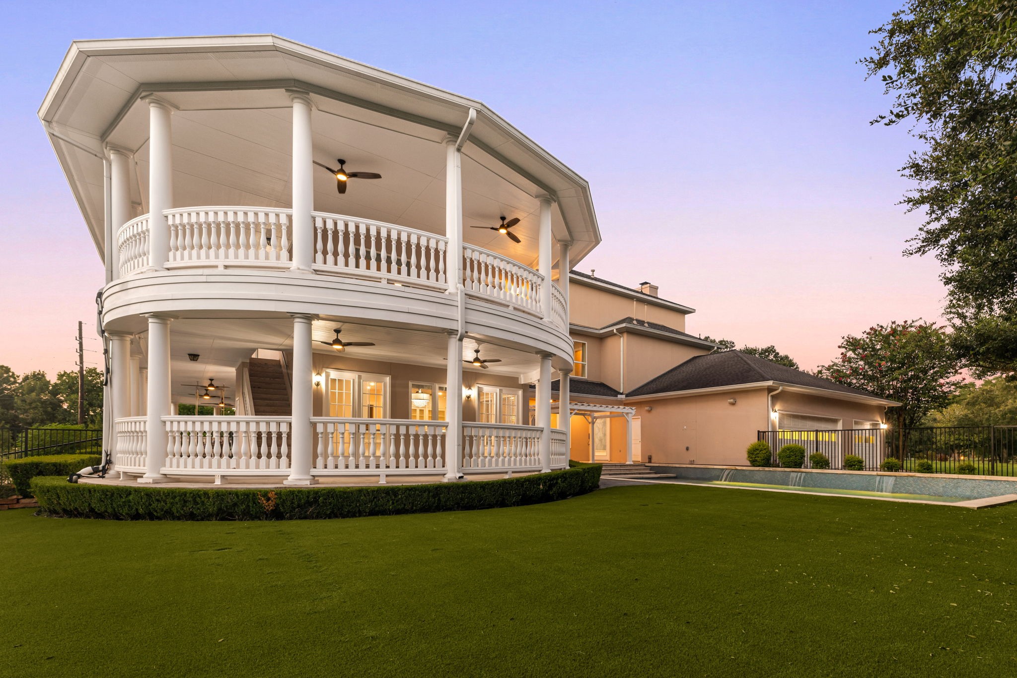 6039 Franz Road Katy, TX 77493 - Photo 38 of 49 Twilight settles over the property's sweeping backyard, where the home's grand double-decker veranda commands the view across manicured turf and mature trees.