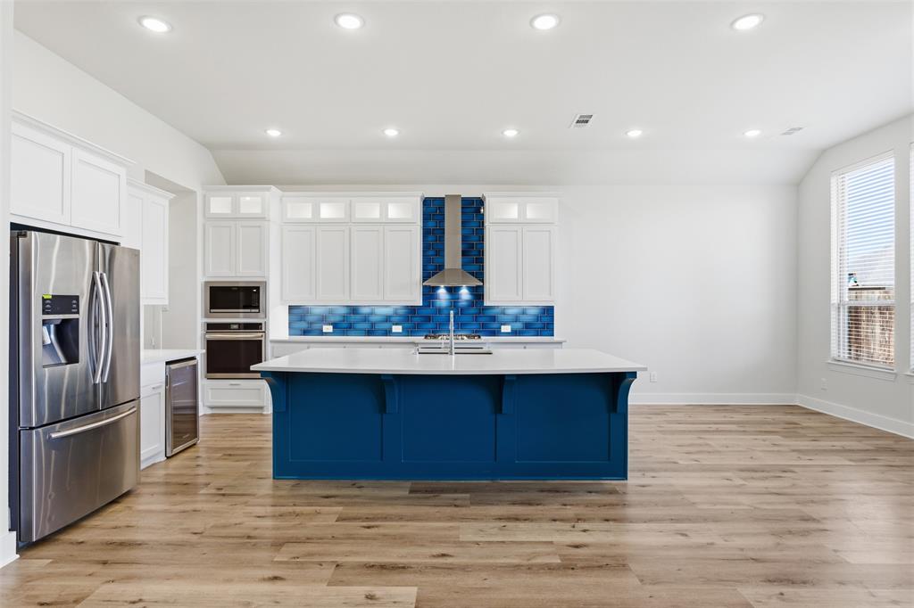 4400 Rocky Rdg Trail Little Elm, TX 75068 - Photo 16 of 40 a kitchen with kitchen island a sink wooden floor and stainless steel appliances