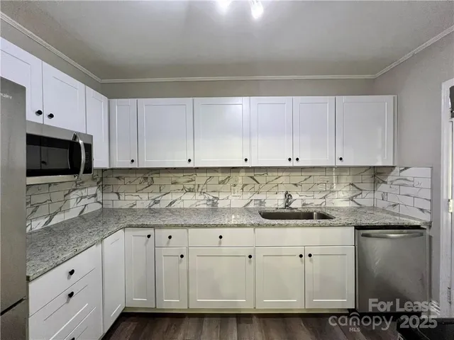 a kitchen with granite countertop white cabinets and stainless steel appliances