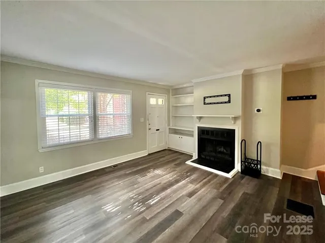 an empty room with windows a fireplace and wooden floor