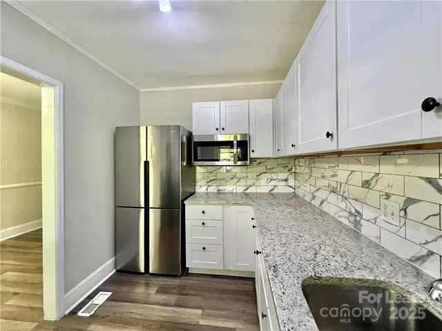 a kitchen with granite countertop white cabinets and stainless steel appliances