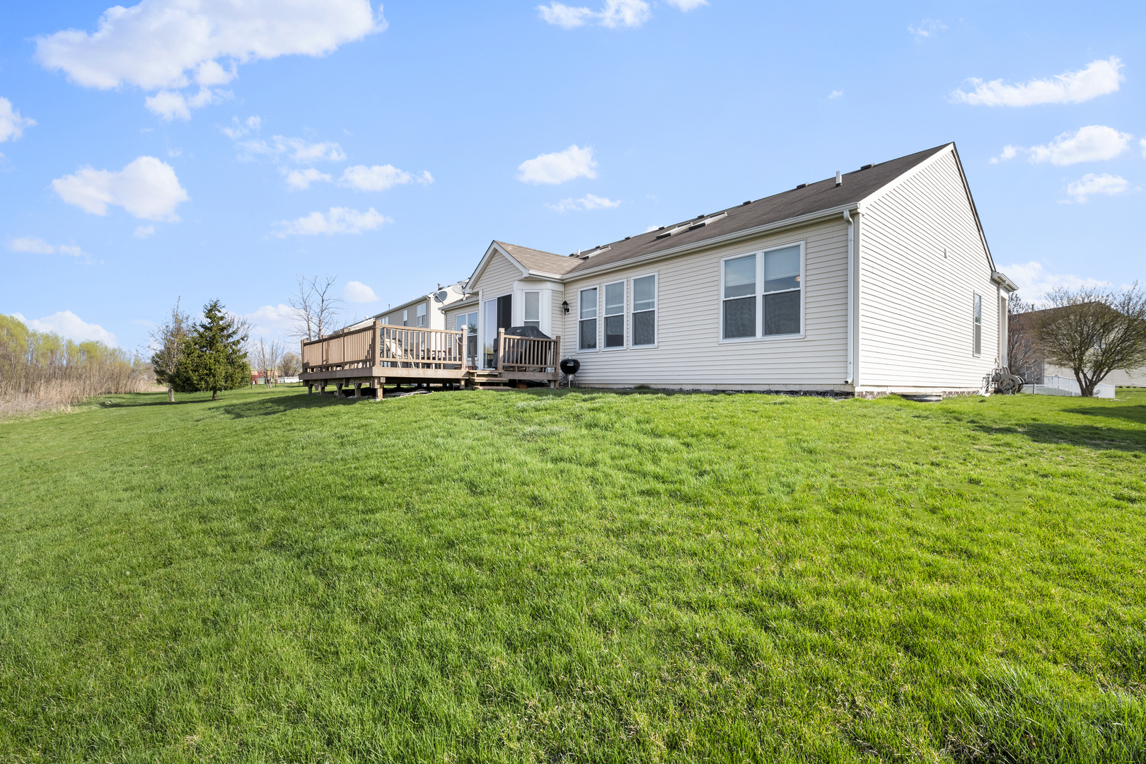 25420 Spring Street Manhattan, IL 60442 - Photo 4 of 27 a house that is sitting in the grass with large trees and plants