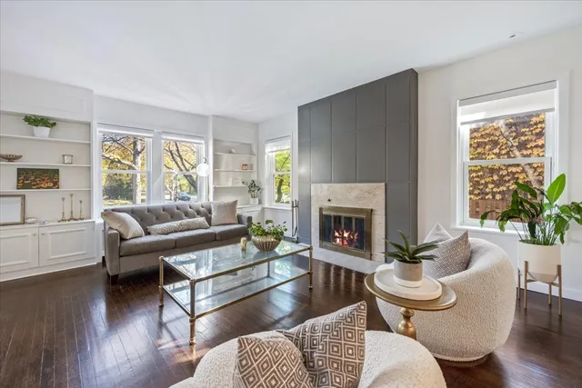 a living room with furniture a fireplace a potted plant and a large window