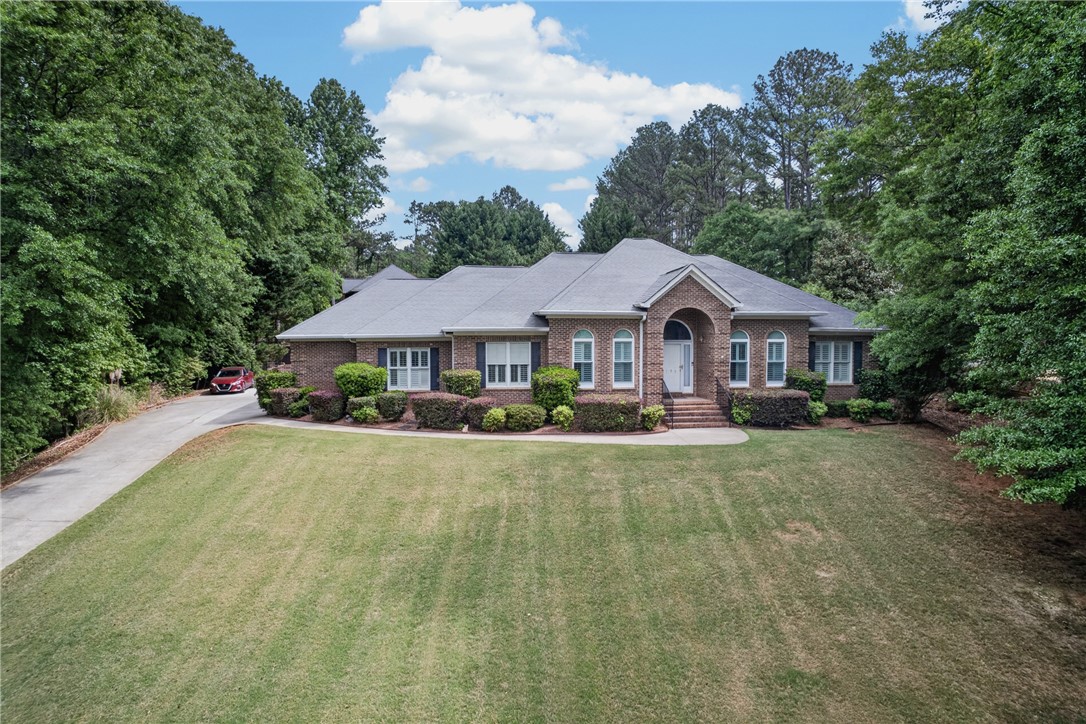 This spacious brick residence is nestled amongst lush trees, offering a serene and private setting.