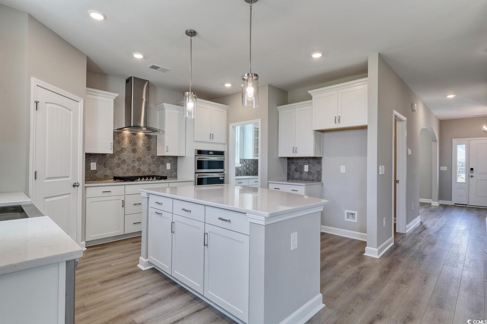 4035 Bucolic Loop Myrtle Beach, SC 29588 - Photo 8 of 39 Kitchen with backsplash, white cabinetry, light wo