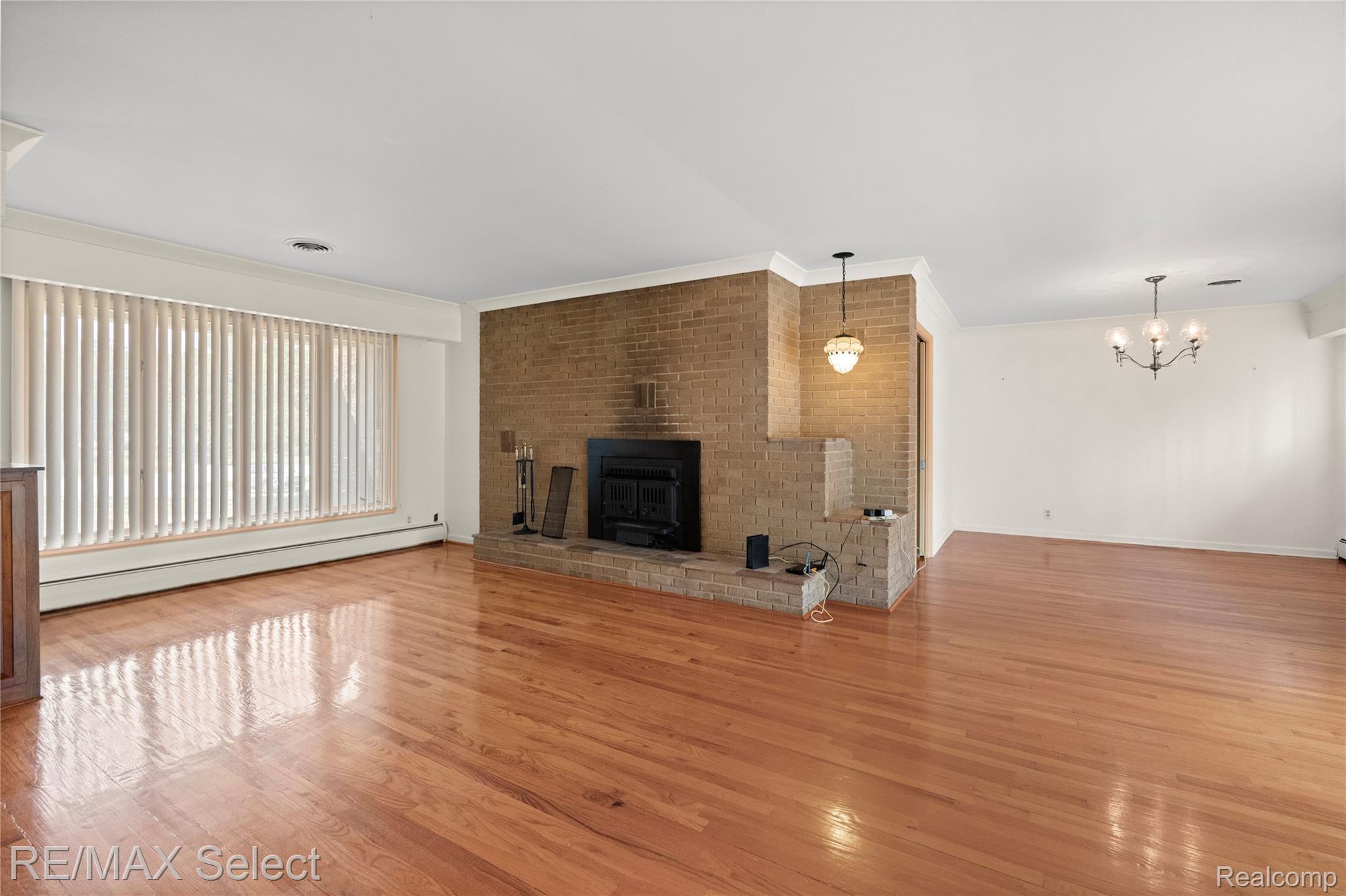 11080 Lapeer Road Davison, MI 48423 - Photo 42 of 64 Hardwood flooring, brick fireplace, large windows, crown molding, and a chandelier