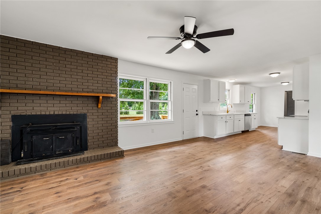300 Vandiver Road Anderson, SC 29621 - Photo 8 of 30 A welcoming interior with brick fireplace and rich hardwood flooring flows into a bright kitchen space.