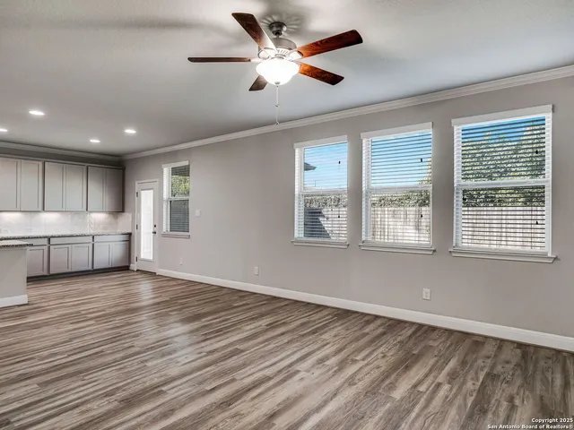 a view of an empty room with window and wooden floor