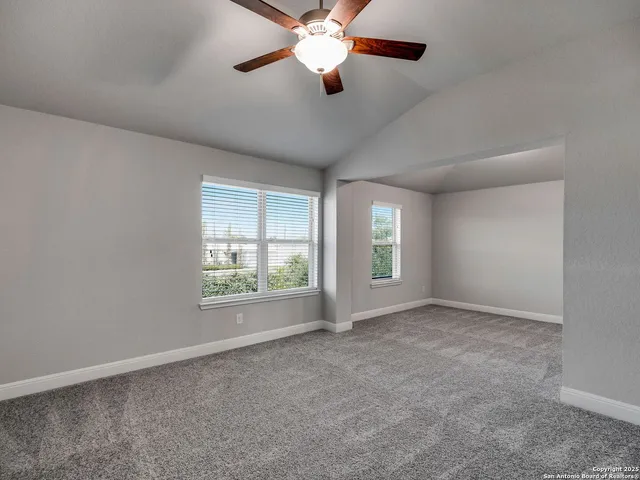 a view of an empty room with window and chandelier fan