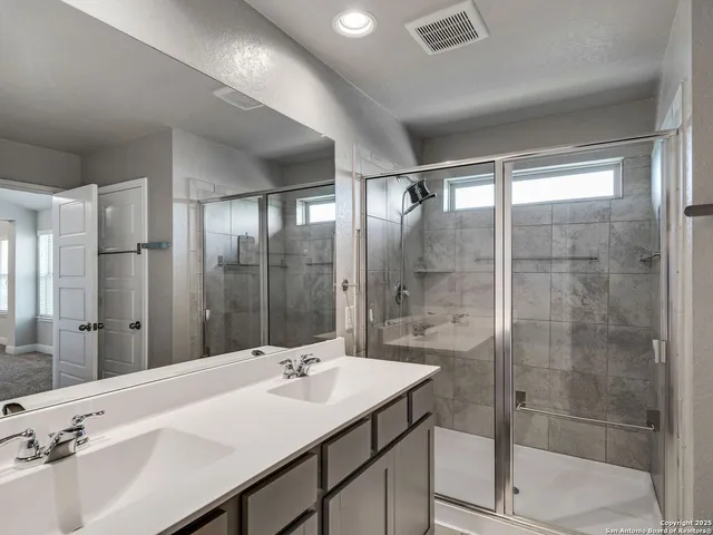 a bathroom with a sink shower and a mirror