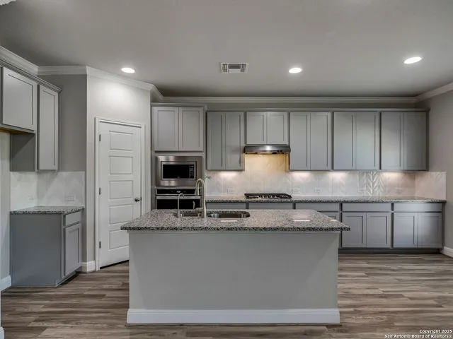 a kitchen with kitchen island granite countertop a stove sink and cabinets