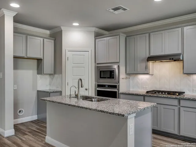 a kitchen with granite countertop a sink a counter space stainless steel appliances and cabinets