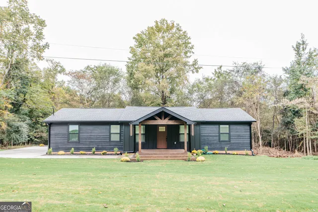 a front view of a house with a garden and trees