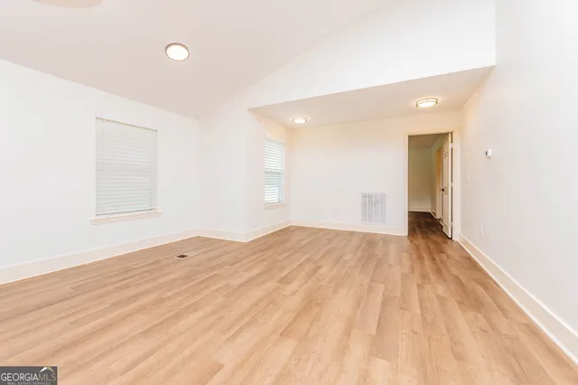 a view of empty room with wooden floor and window