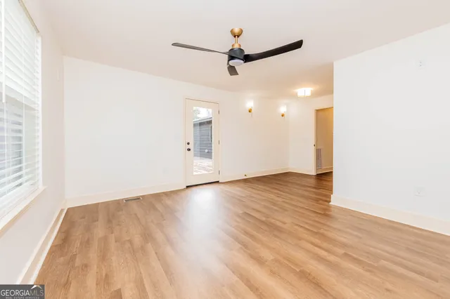 a view of empty room with wooden floor and fan