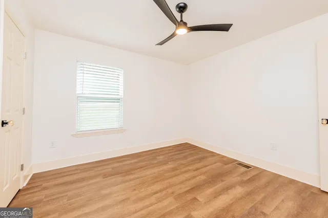 an empty room with wooden floor closet and ceiling fan