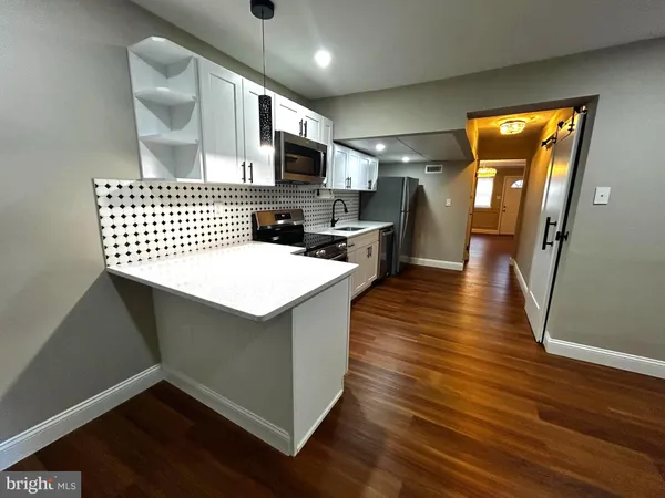 a kitchen with a sink a microwave cabinets and wooden floor