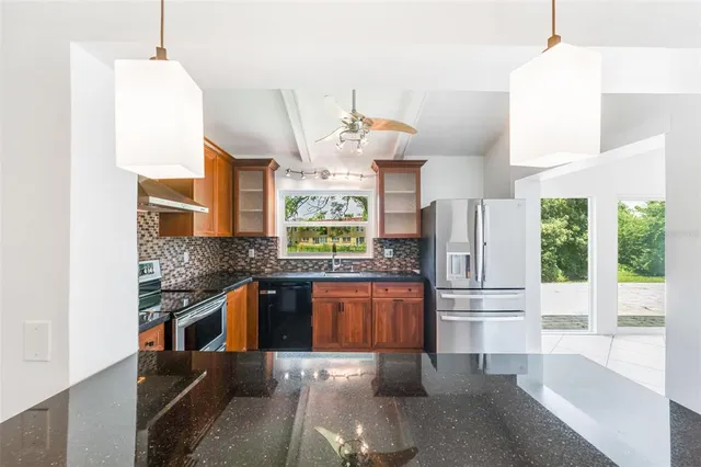 a kitchen with stainless steel appliances granite countertop a refrigerator a stove and a wooden floors