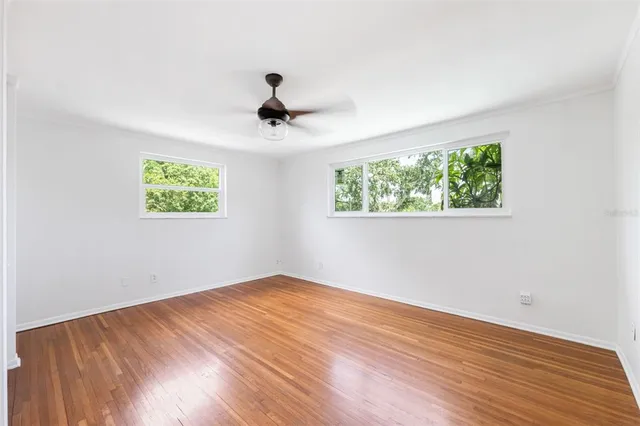 a view of a big room with wooden floor and windows