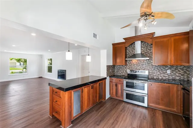 a kitchen with stainless steel appliances kitchen island granite countertop wooden floors and a sink