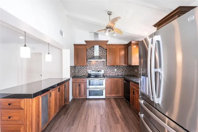 a kitchen with stainless steel appliances granite countertop a refrigerator a sink dishwasher a stove and white countertops with wooden floor