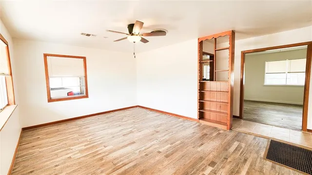 an empty room with wooden floor closet and windows