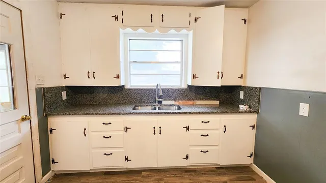 a kitchen with granite countertop white cabinets and sink
