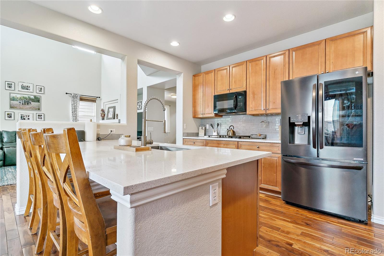 3477 Softwind Point Castle Rock, CO 80108 - Photo 16 of 50 a kitchen with stainless steel appliances granite countertop a refrigerator a stove and a sink with wooden floor