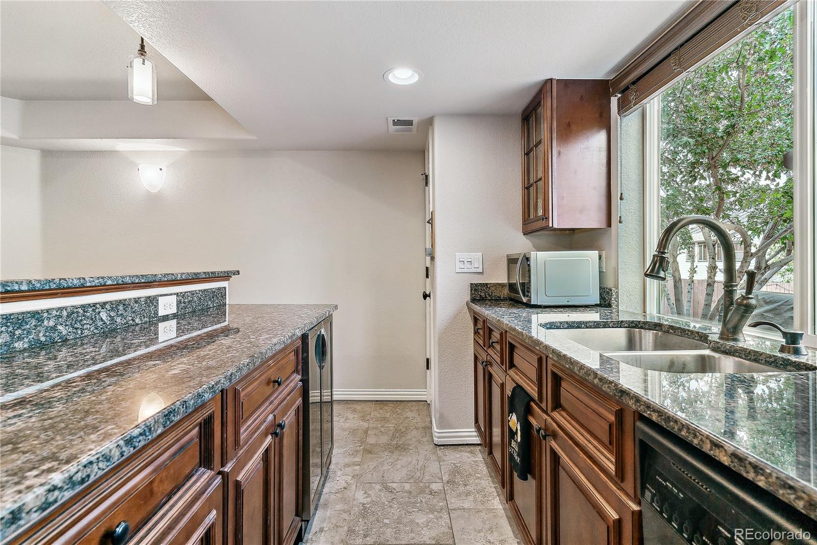 3477 Softwind Point Castle Rock, CO 80108 - Photo 36 of 50 a kitchen with granite countertop a sink a stove and a wooden floor