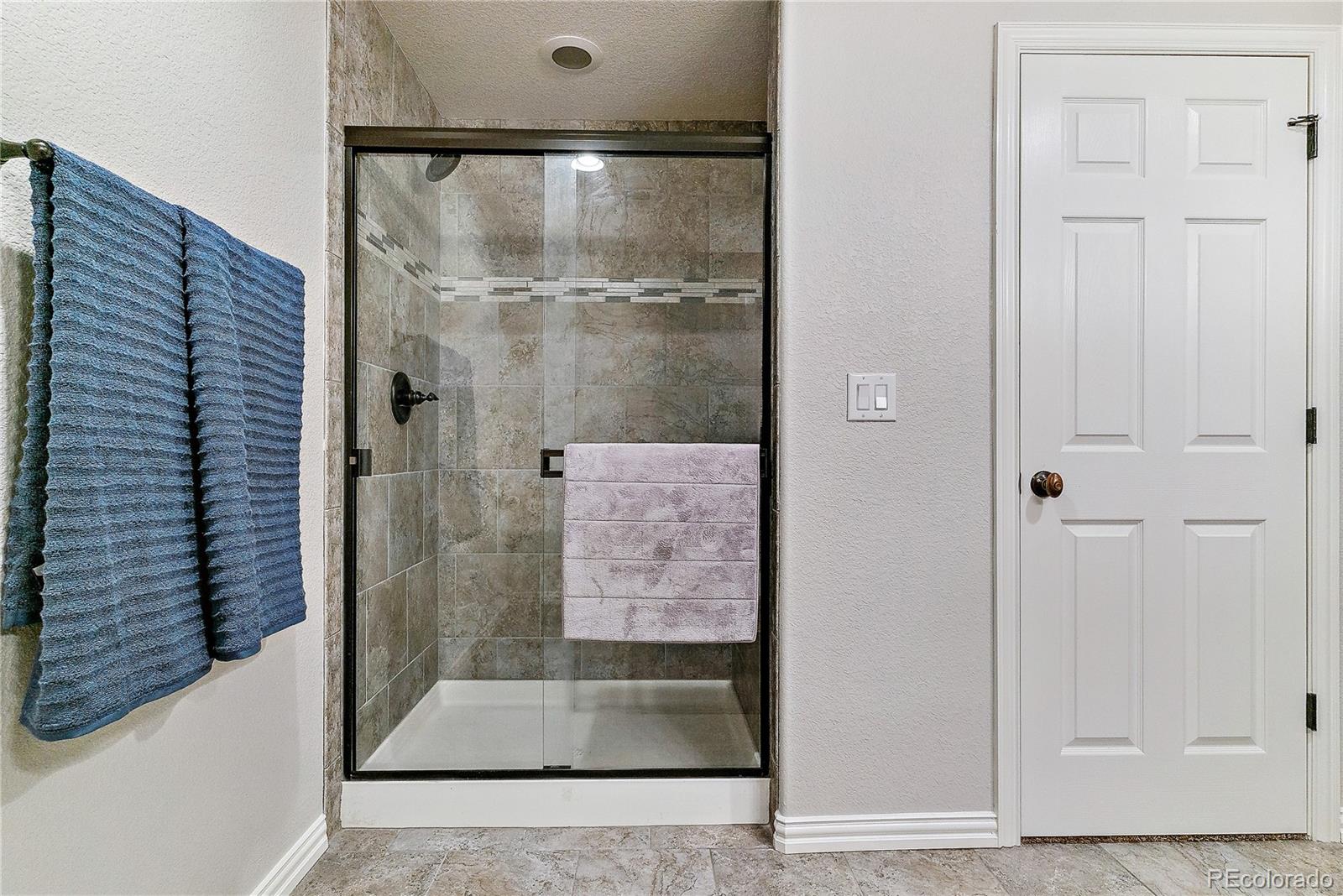 3477 Softwind Point Castle Rock, CO 80108 - Photo 42 of 50 a bathroom with a glass shower door