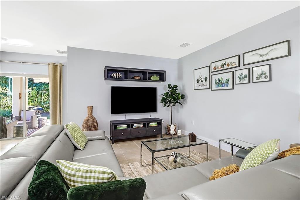 690 Hadley Place East Naples, FL 34104 - Photo 11 of 27 a living room with furniture a flat screen tv and a large window