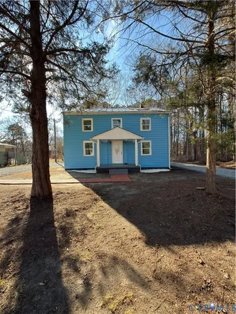 a front view of a house with a yard and large trees