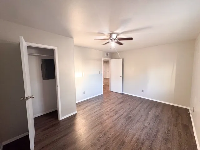 an empty room with wooden floor and ceiling fan