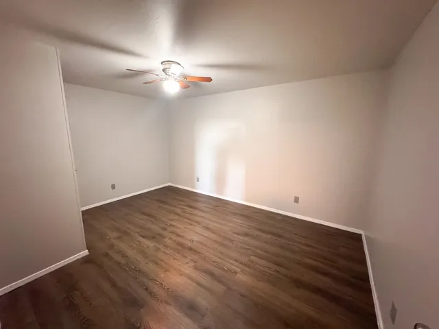 an empty room with wooden floor and fan
