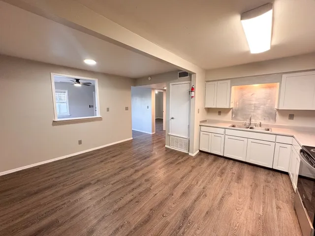 a large white kitchen with a lot of white cabinets and wooden floor