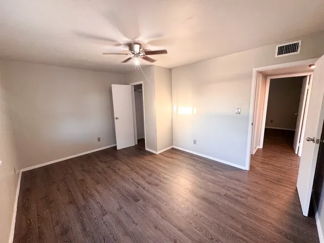 an empty room with wooden floor and ceiling fan