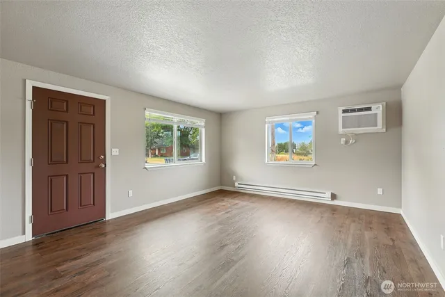an empty room with wooden floor and windows