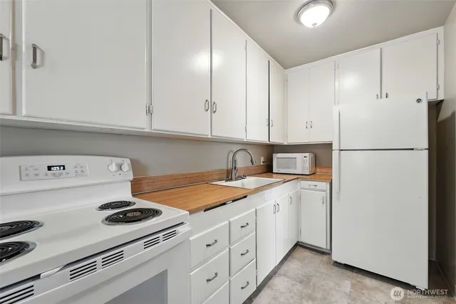 a kitchen with a sink a stove and white cabinets