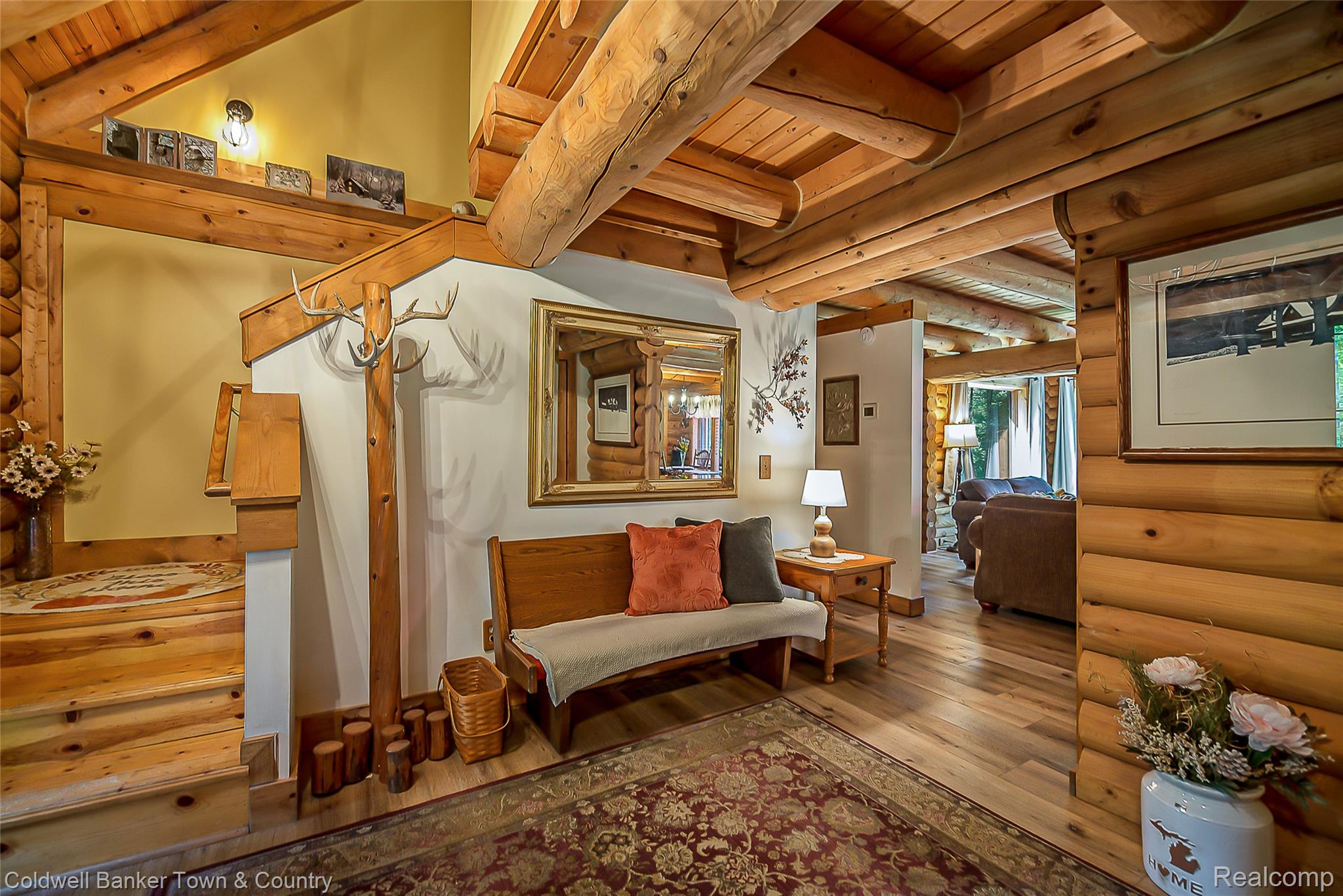 7023 Munsell Road Howell, MI 48843 - Photo 19 of 55 Natural wood log walls, timber beam ceiling, wood-finish flooring, and a solid wood staircase