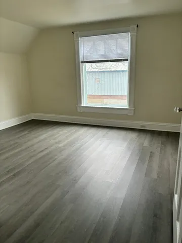 an empty room with wooden floor and a window