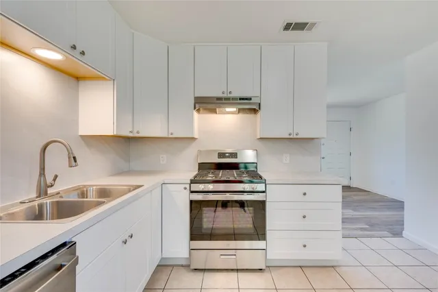 a kitchen with white cabinets and appliances