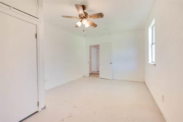 an empty room with a window and a ceiling fan